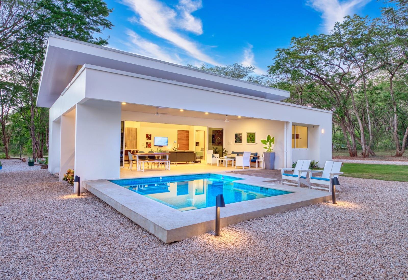 Costa Nativa at dusk, the lit pool reflecting the open living space