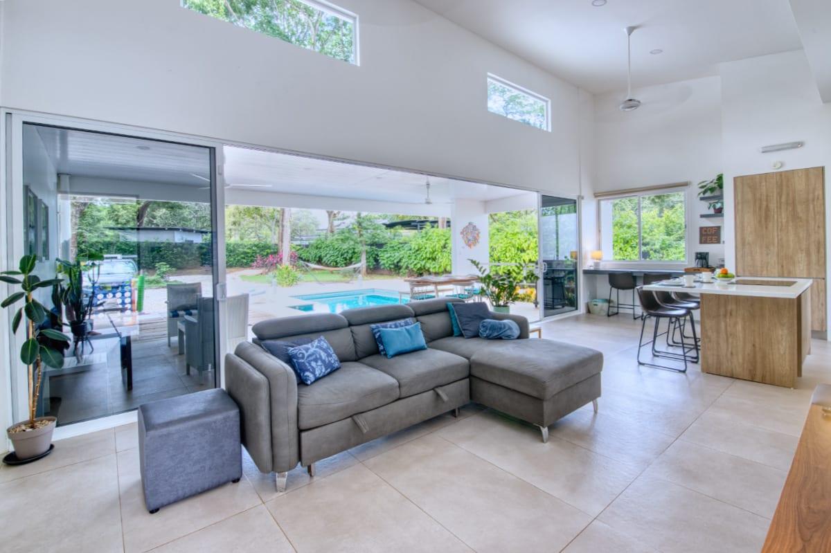 The living room with the sliding glass doors drawn back, opening onto the terrace and pool beyond